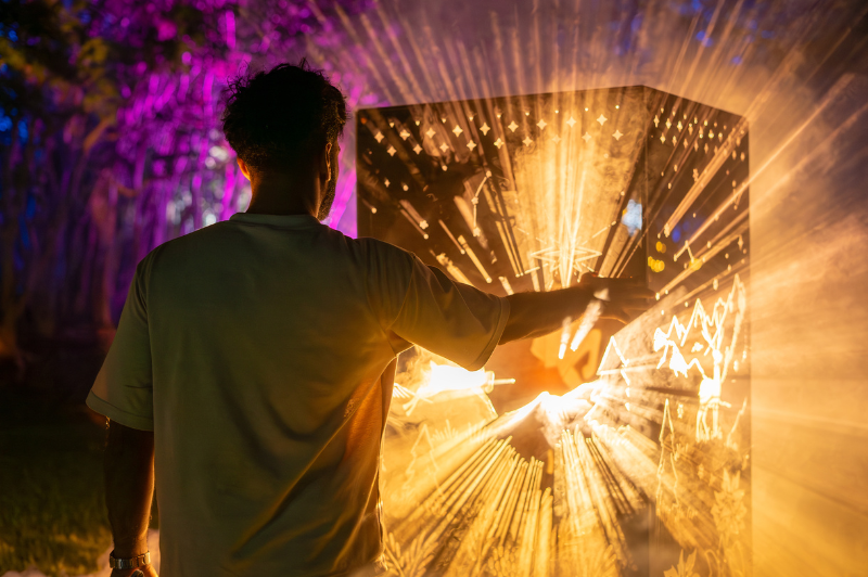 Man reaching out to an orange/yellow-lit box with light rays coming out of it.