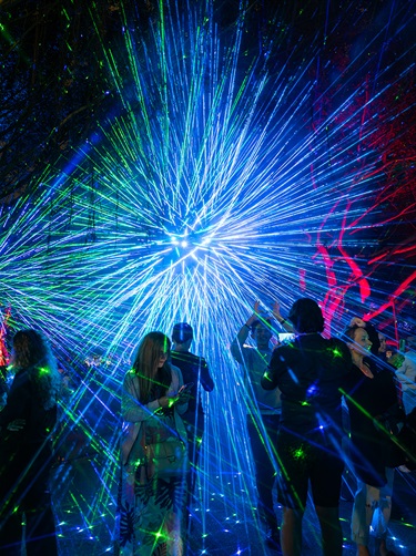 Several people walking around in the laser display