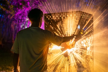Teenager reaching out to glowing light installation